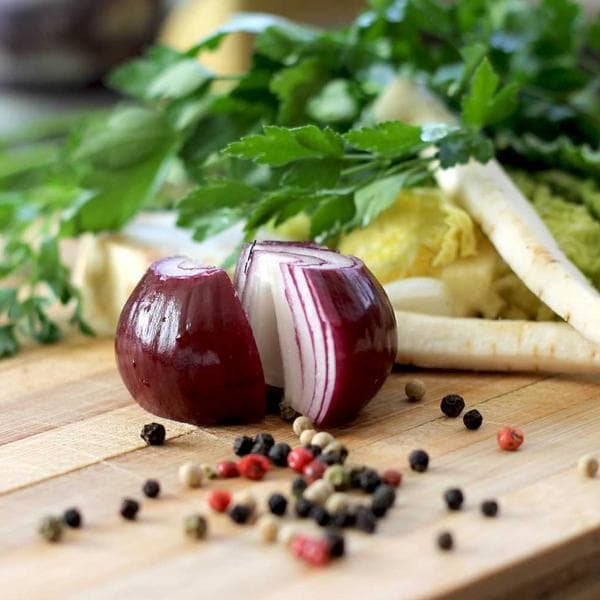 A red onion and peppercorns on a chopping board, from a ChatGPT ad