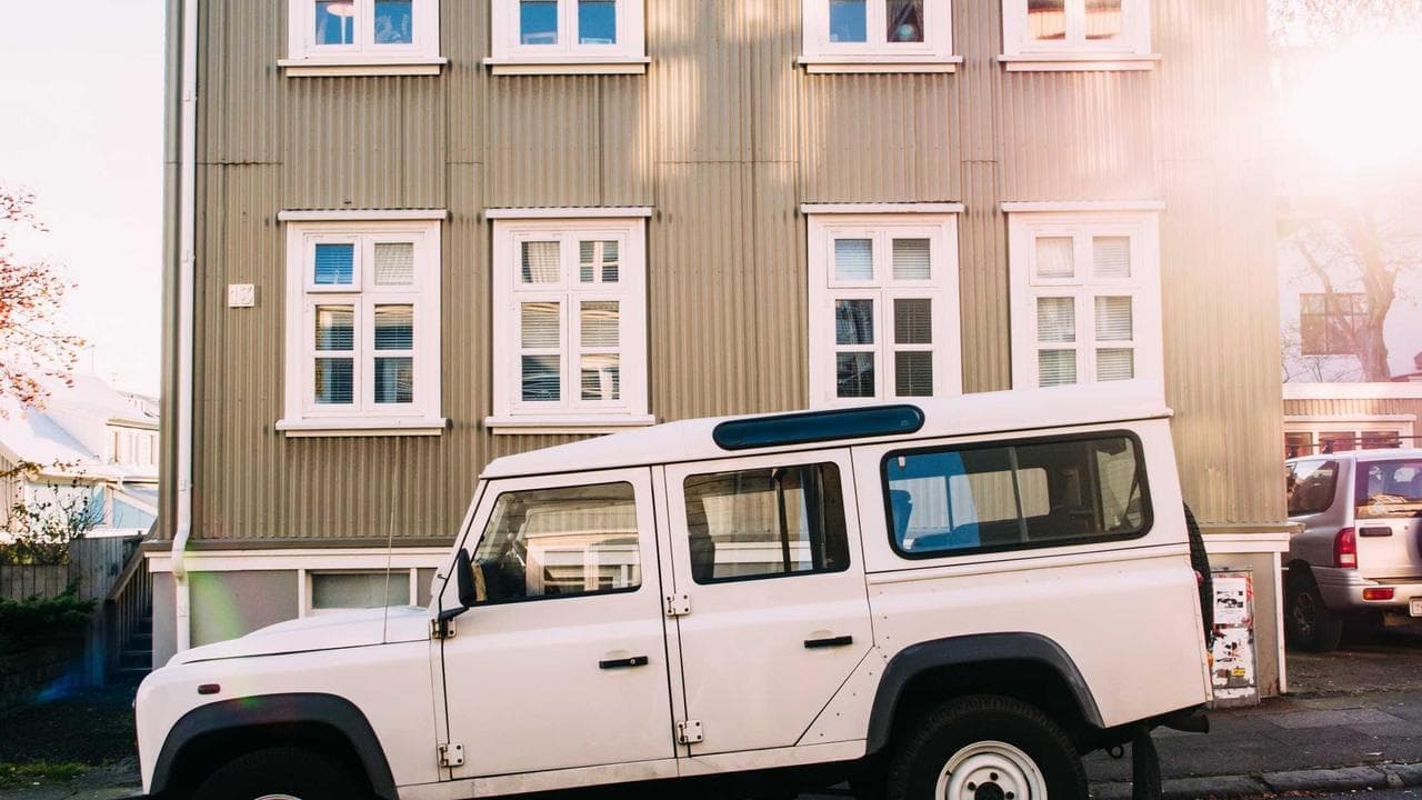 A white Land Rover outside a wooden house