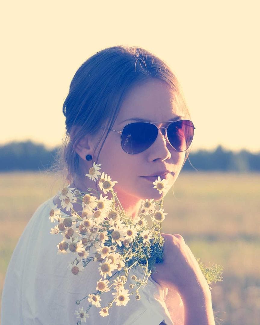 A woman in sunglasses holding wild flowers, from a reel